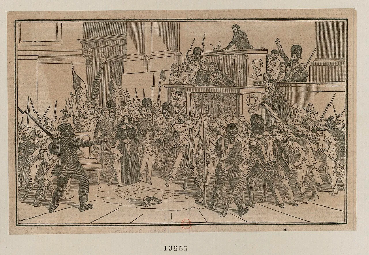 Gravure : dans la salle de la Chambre, des hommes armés de fusils et de piques entourent une femme en noir et deux enfants, sous la tribune où parle un orateur.